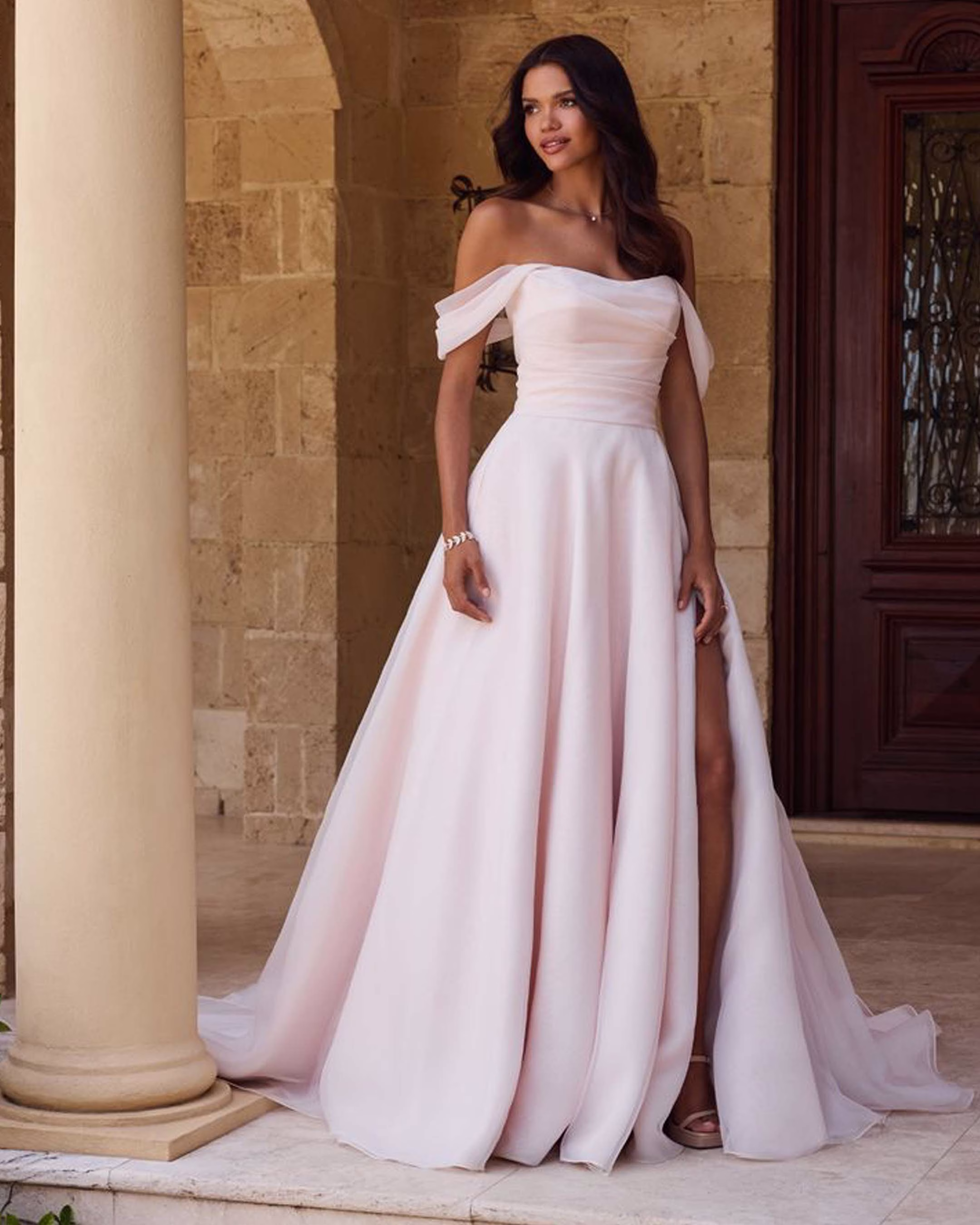 Sophia Tolli Rianne Y3125 organza ball gown wedding dress with strapless sweetheart neckline, draped bodice, flowing skirt with slit, pockets, and detachable straps.