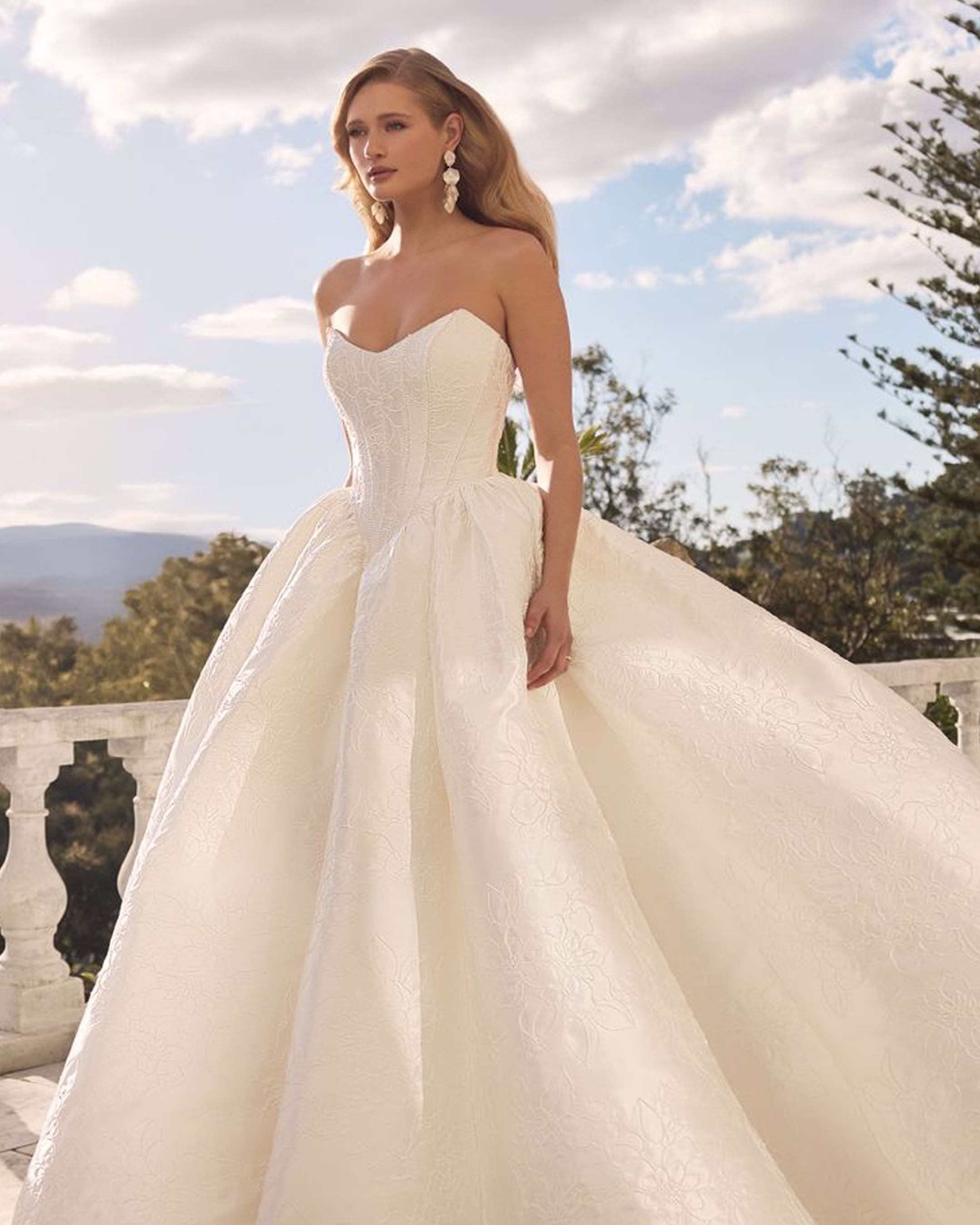 Sophia Tolli Rosalie ST673 mikado ball gown wedding dress with strapless scoop neckline, boned corset bodice, basque waist, pearl details, full skirt, and chapel train.