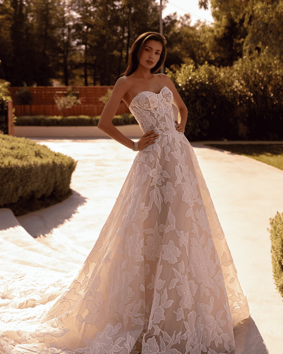 Demetrios Style 1524 A-line wedding dress with a structured corset bodice, floral lace appliqués, layered tulle skirt, and dramatic cathedral train.
