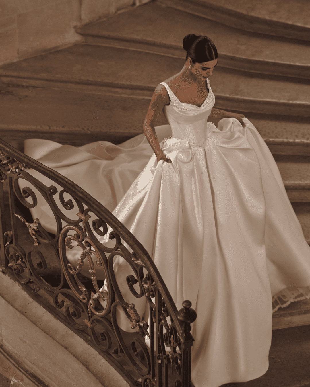 Milla Nova Alaia mikado A-line wedding dress with a cinched waist corset, draped heart-shaped neckline, pearl embellishments, wide straps, and long train.