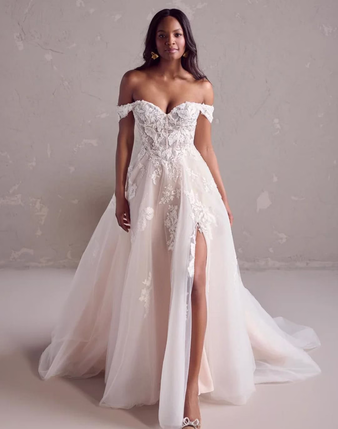 Rebecca Ingram Janice A-line wedding dress featuring beaded floral lace, illusion bodice, sweetheart neckline, and off-the-shoulder cap sleeves.