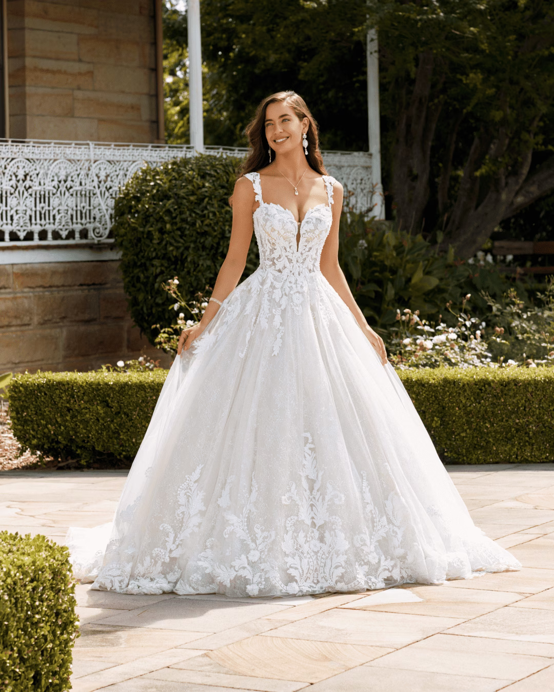 Sophia Tolli Milana ST2226 lace ball gown wedding dress with a sweetheart neckline, beaded lace corset bodice, detachable lace cap sleeves, full tulle skirt, and romantic train.