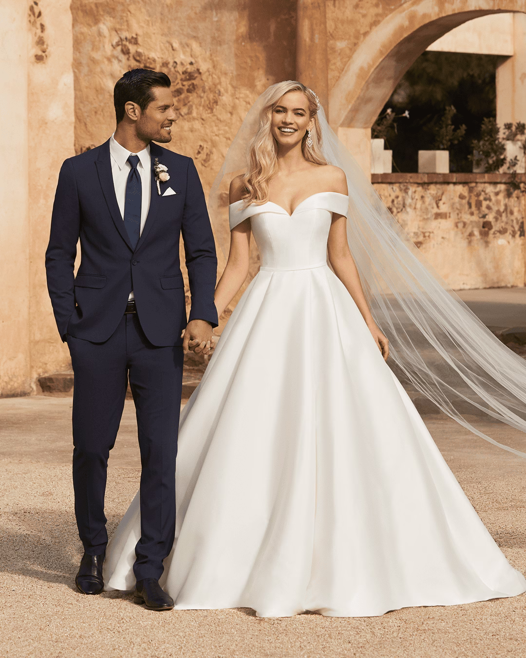 Sophia Tolli Kennedy Y12014 Pearl Mikado ball gown wedding dress with sweetheart neckline, off-the-shoulder straps, waist belt, pleated full skirt, pockets, and chapel train.