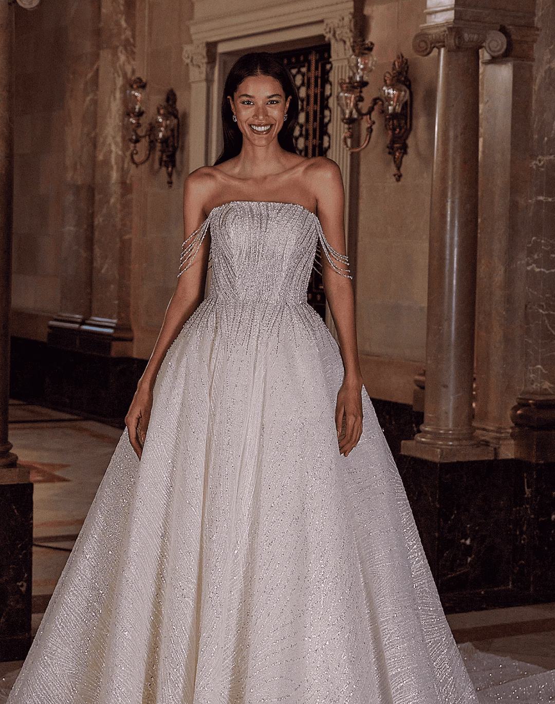 Demetrios DP548 celestial beaded shimmer tulle ball gown wedding dress with a strapless neckline, sculpted corset bodice, crystal off-the-shoulder straps, full skirt, chapel train, and detachable cape.